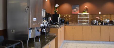 A modern kitchen with stainless steel appliances, a coffee station, and a decorative flower arrangement.