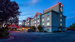 A multi-story hotel with a prominent 'Best Western Plus' sign, a parking lot, and a building entrance with a red neon sign. - Best Western Plus Liberty Lake Inn (Liberty Lake)