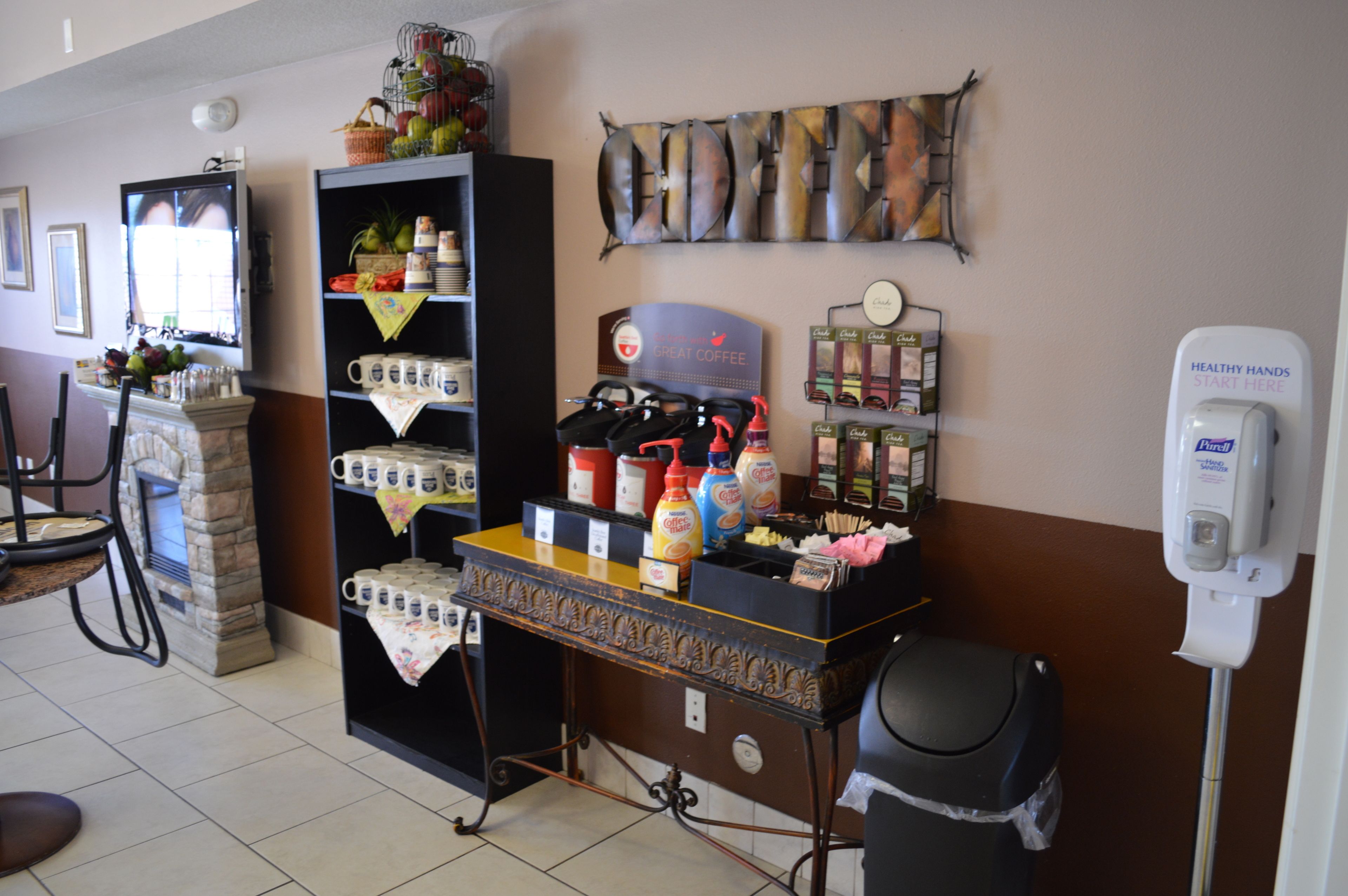 A kitchen area with a coffee station, a fish-themed wall decoration, and a hand sanitizer dispenser.