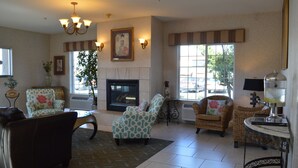 A spacious living room with a fireplace, comfortable seating, and large windows offering views of the outside. - Best Western Plus Liberty Lake Inn (Liberty Lake)