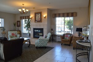 A spacious living room with a fireplace, comfortable seating, and large windows offering views of the outside.