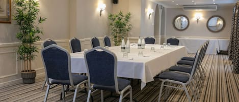 A conference room with a long table, chairs, and potted plants.
