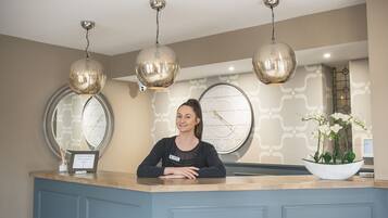 A reception desk with a clock, decorative lights, and a flower arrangement.