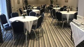 Comedor de hotel con mesas redondas, sillas y una alfombra a rayas.