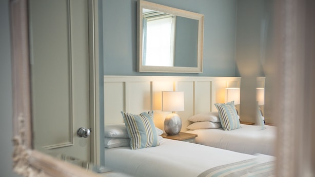 Une chambre d’hôtel avec deux lits, un grand miroir au-dessus de la tête de lit et des lampes de chevet.