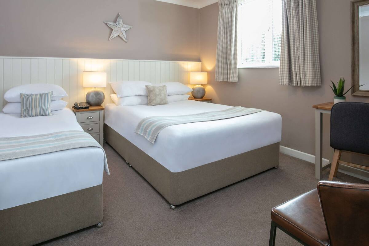 Une chambre d’hôtel avec deux lits, un bureau et une chaise.