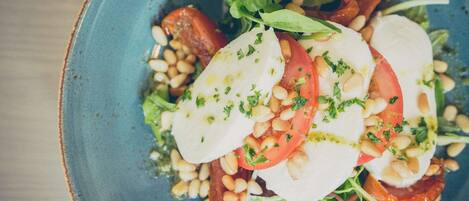 Une assiette de salade Caprese, composée de tomates, de mozzarella et de pignons de pin, et agrémentée d’herbes fraîches.