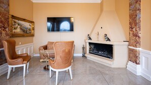 A living room with a fireplace, a television, and a painting on the wall. - Milling Hotel Plaza (Odense)