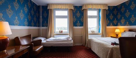 Una habitación de hotel con dos camas, un escritorio, una silla y una ventana con cortinas.