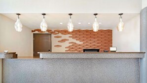 A reception area with a patterned wall, a reception desk, and hanging pendant lights.