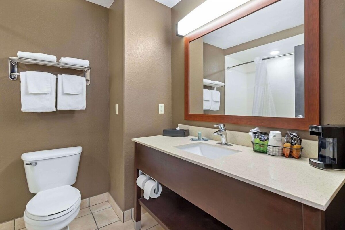 Une salle de bain comprenant des toilettes, un lavabo avec un miroir et un porte-serviettes avec des serviettes.