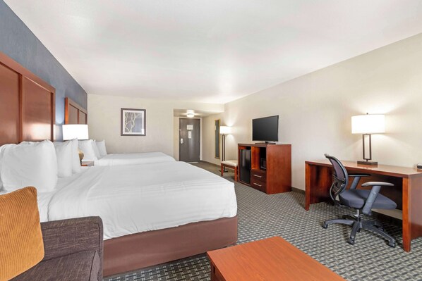 Una habitación de hotel con una cama grande, un escritorio con silla, televisión y una lámpara.