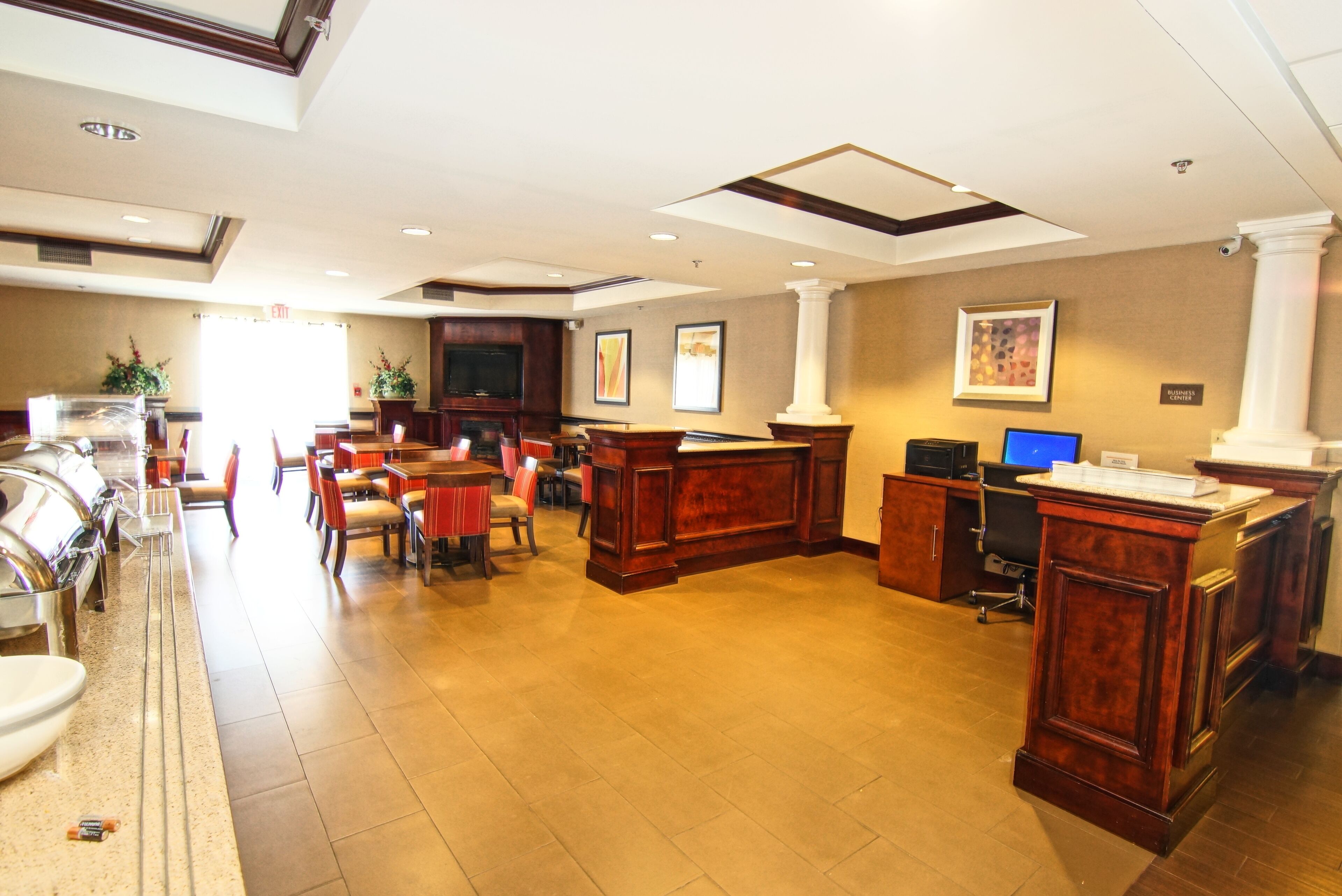A hotel lobby with a reception desk, seating area, and a buffet.