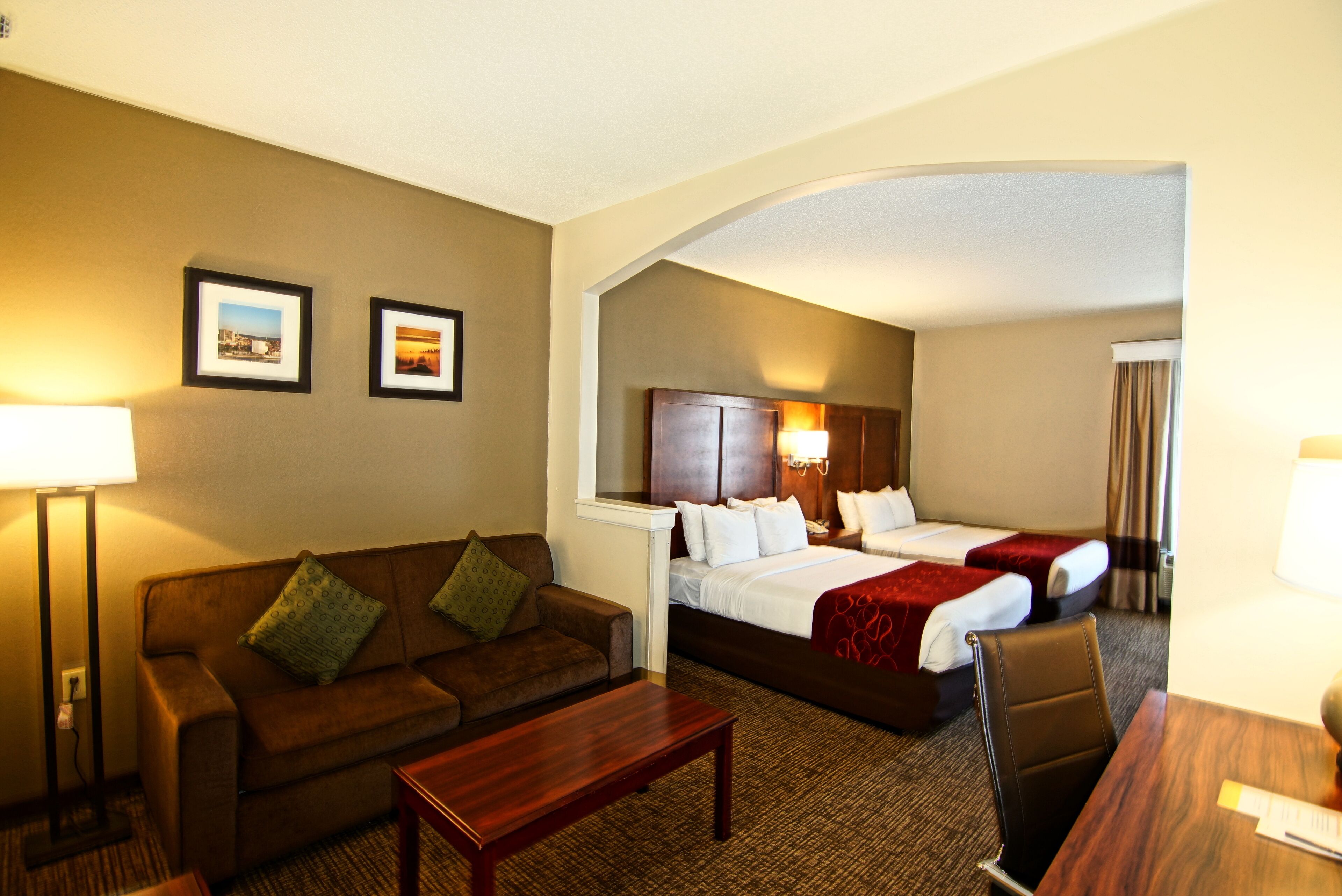 A hotel room with a sofa, a bed, a desk, and a lamp.