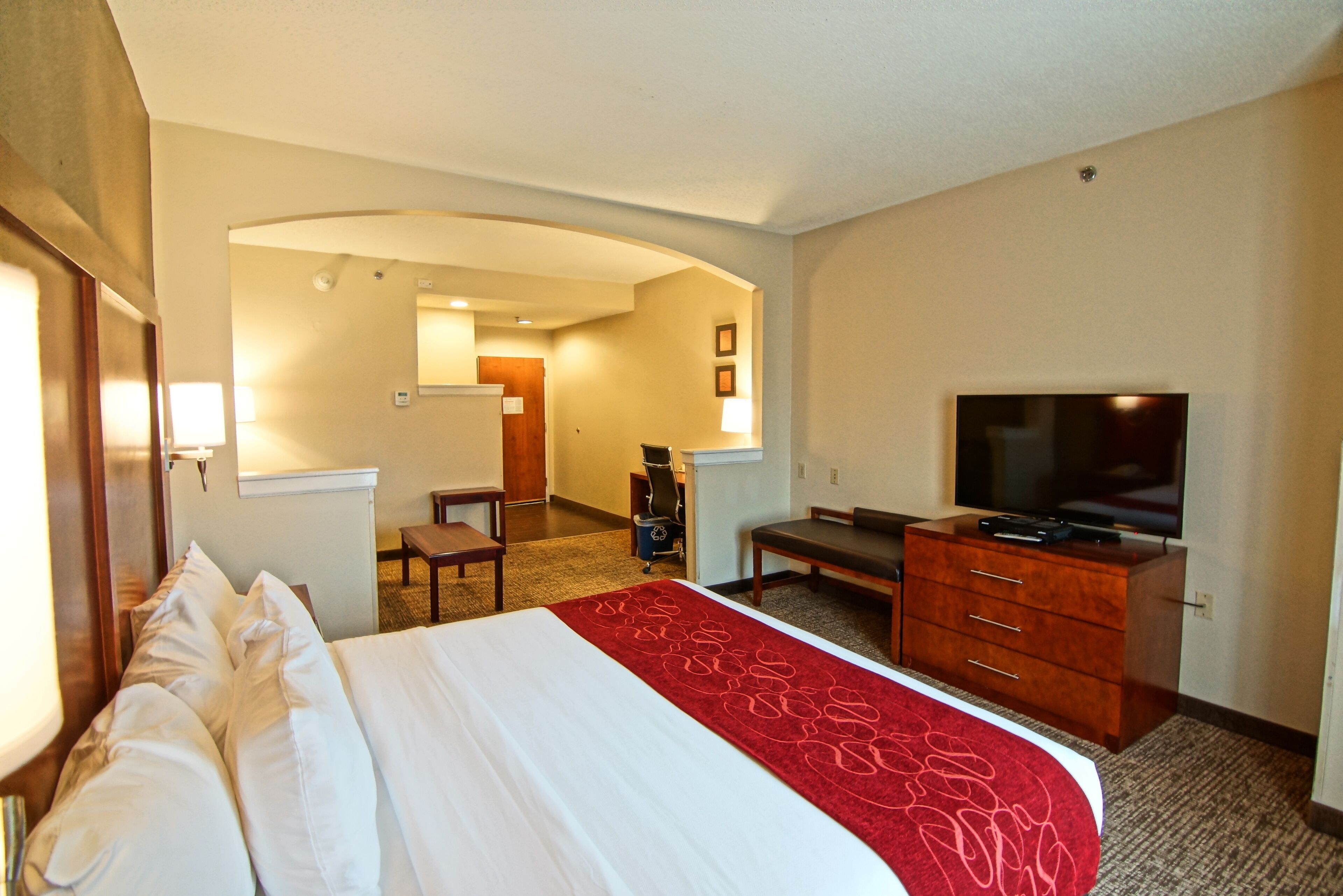 A hotel room with a large bed, a television, a desk, and a chair.
