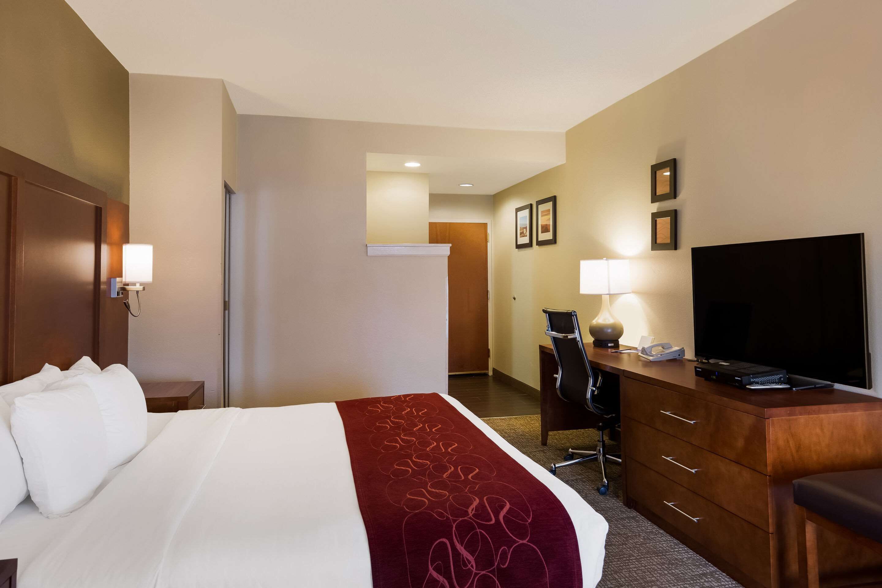 A hotel room with a bed, a desk, a television, and a chair.