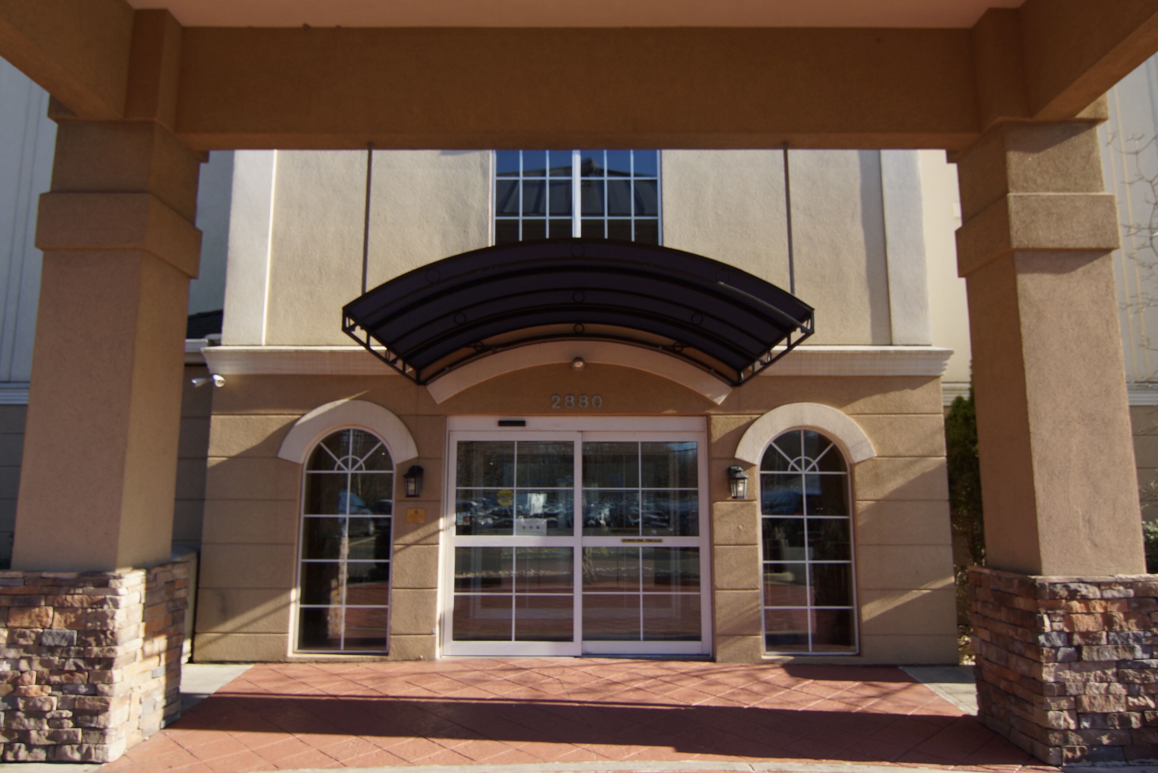 A building entrance with a large arched doorway, stone pillars, and a number "2880" above the entrance.