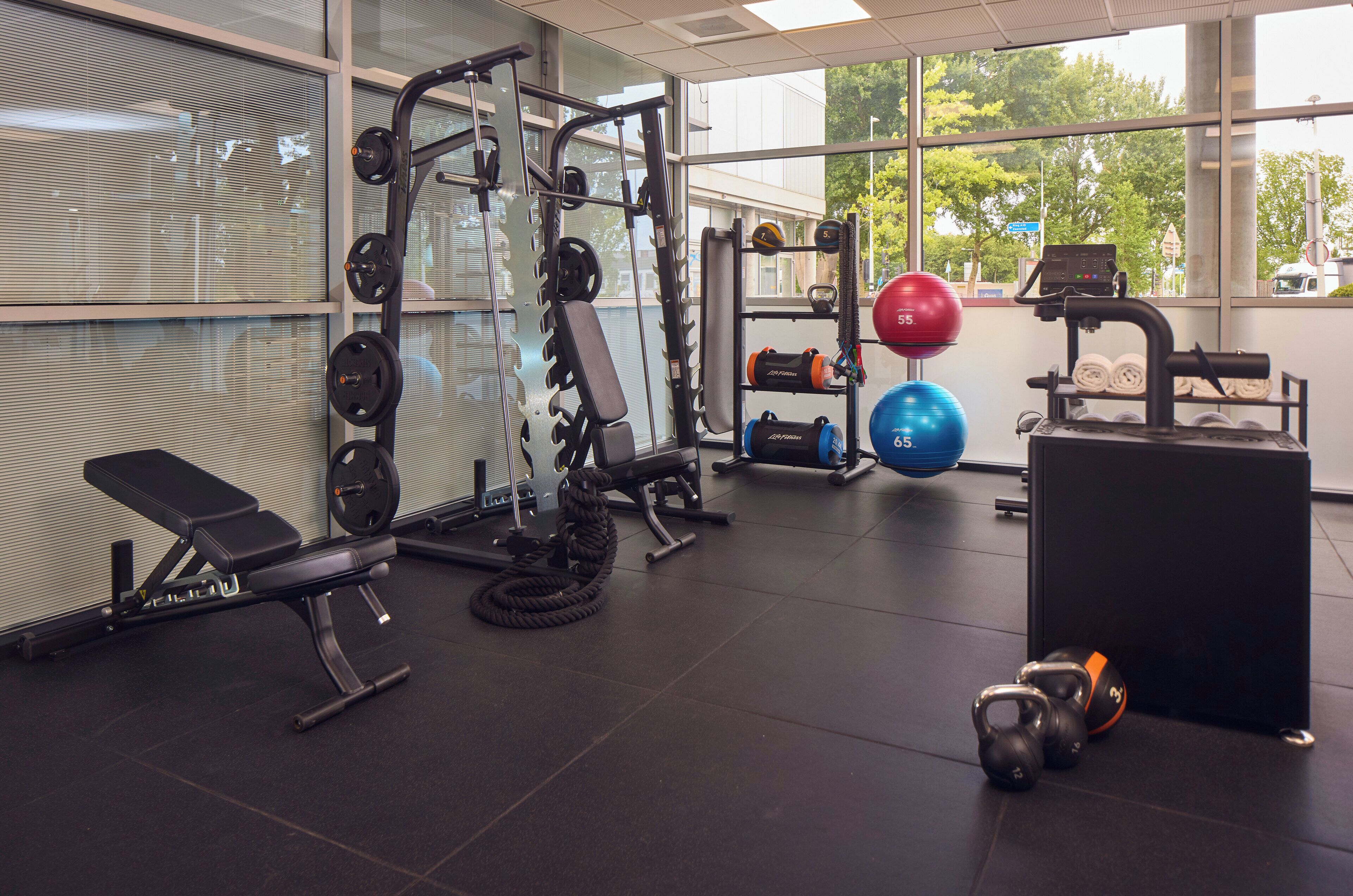 A gym with weightlifting equipment, exercise balls, and a bench.