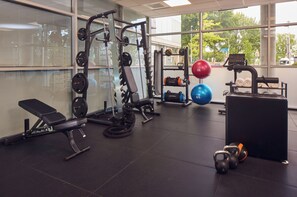 Un gimnasio con equipo de levantamiento de pesas, pelotas de ejercicio y una banca.