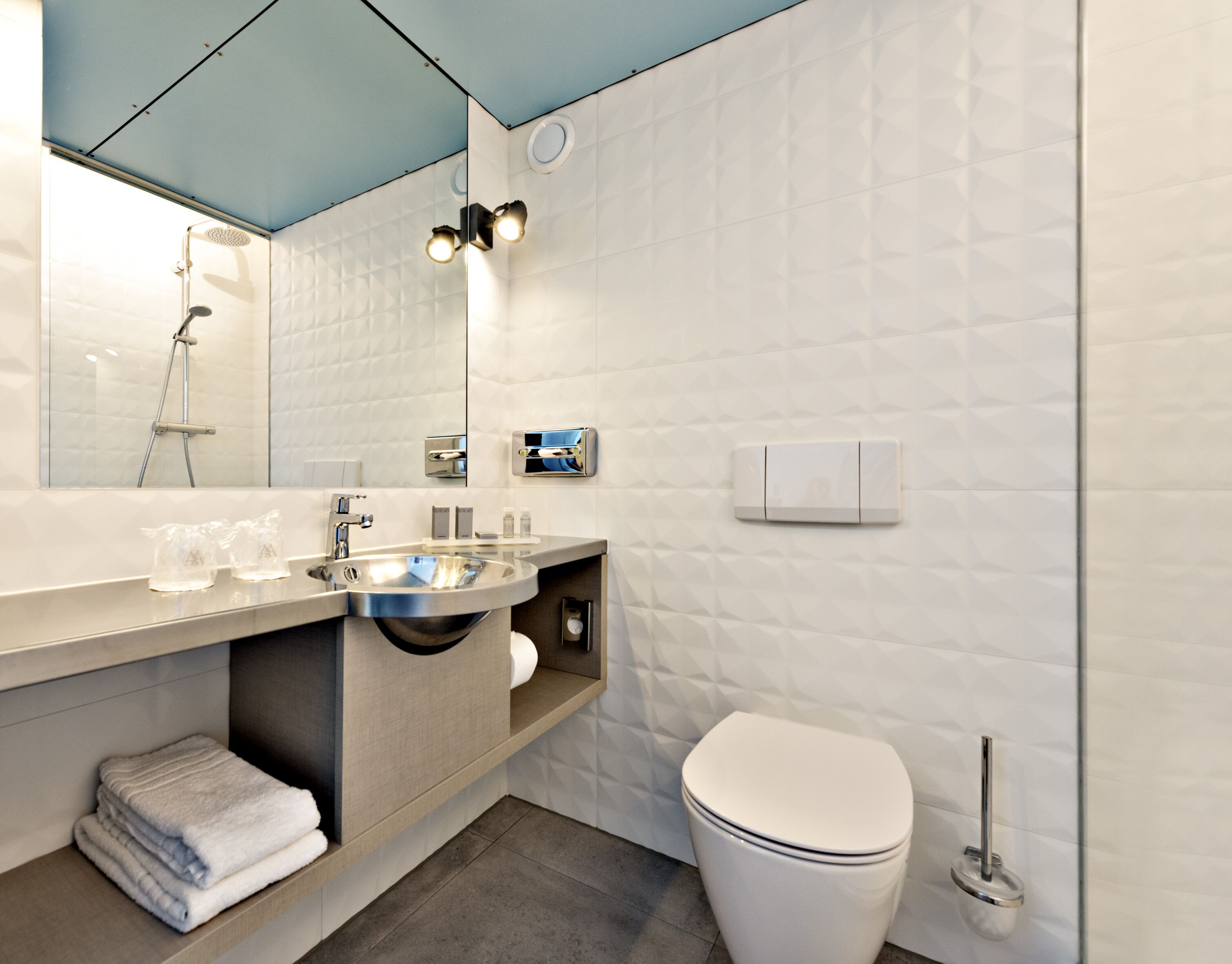 A modern bathroom with a large mirror, a sink, a toilet, and a shower.