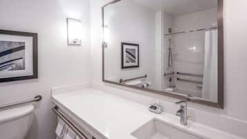 Un baño moderno con un espejo grande, lavamanos blanco y zona de ducha.