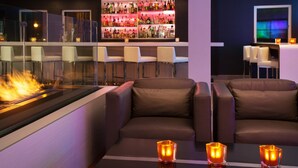 A bar area with a fireplace, leather seating, and a well-stocked liquor shelf. - Aloft by Marriott San Jose Cupertino (San Jose)