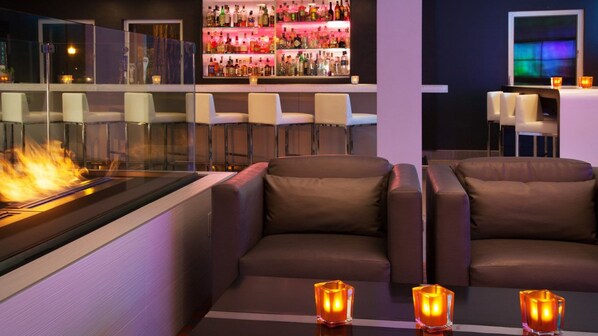 A bar area with a fireplace, leather seating, and a well-stocked liquor shelf. - Aloft by Marriott San Jose Cupertino (San Jose)