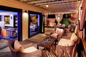 A well-lit outdoor seating area with wicker furniture and a glass coffee table.