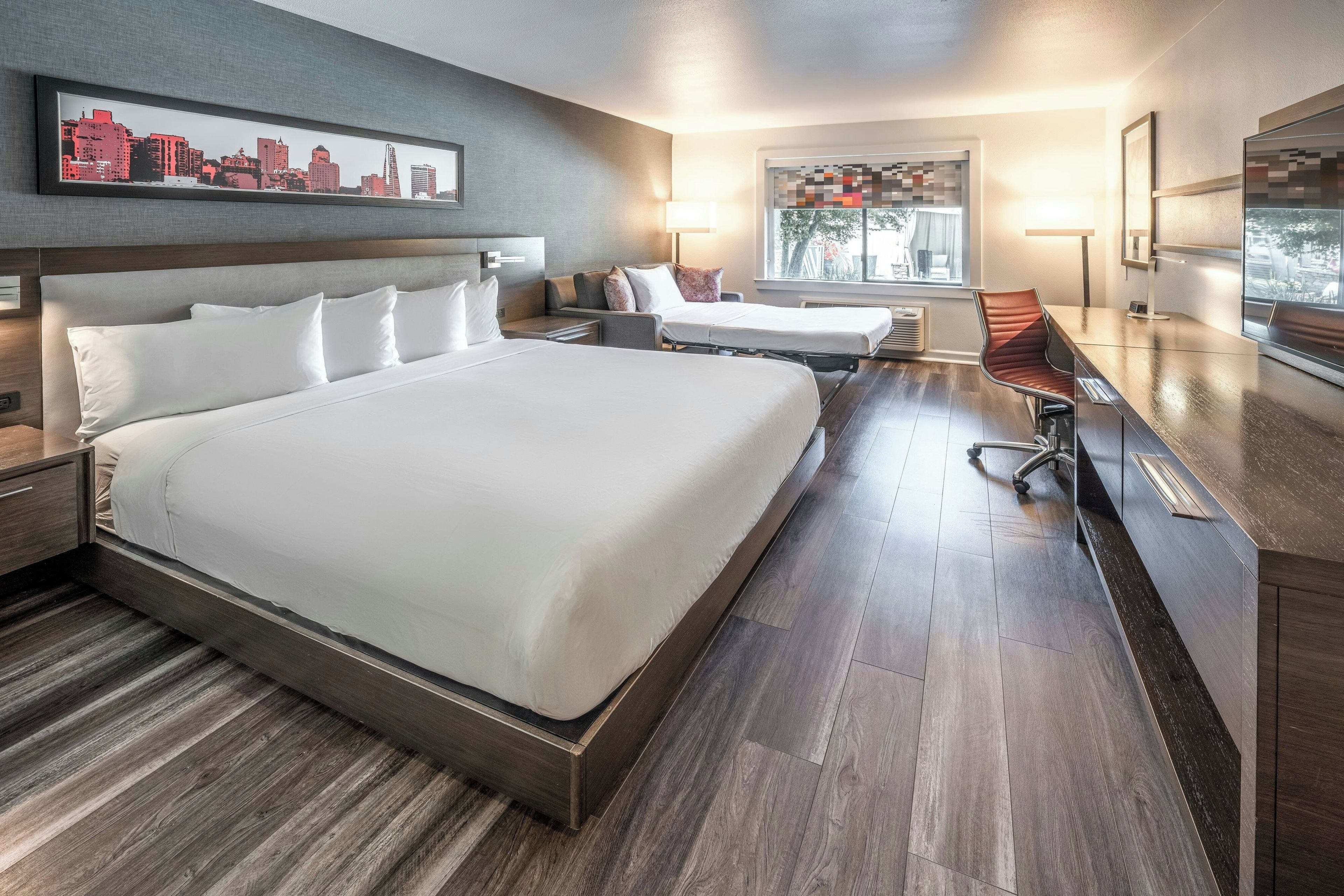 Una habitación de hotel moderna con una cama grande, un escritorio y una silla.