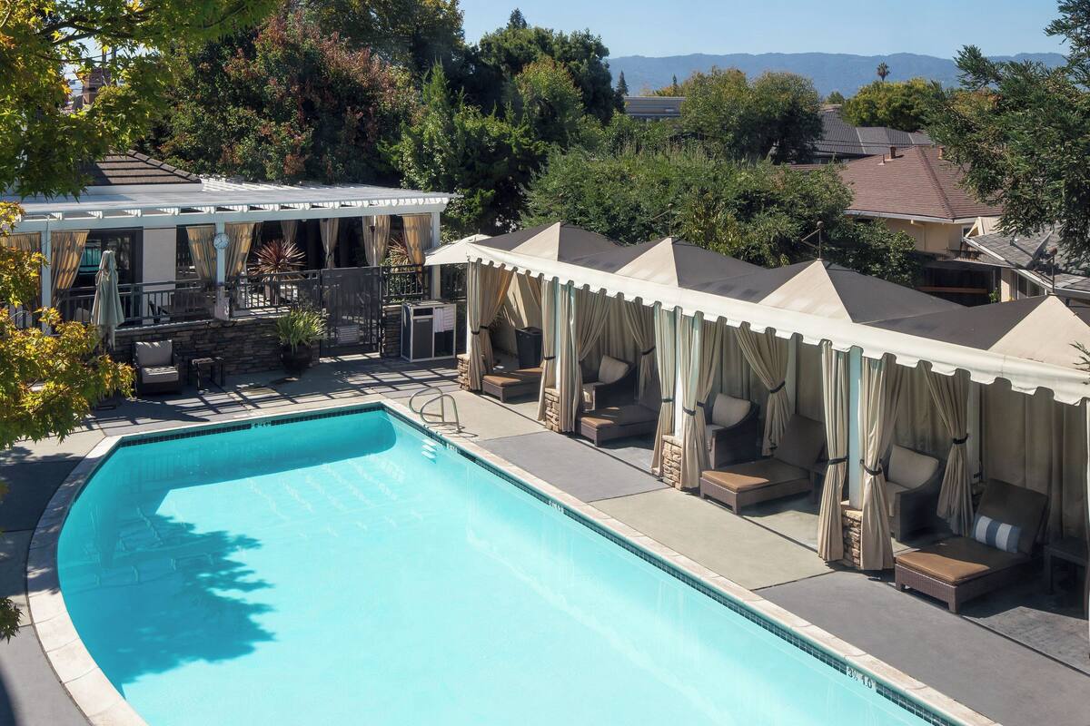 A swimming pool with lounge chairs and a covered seating area.