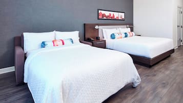 Habitación de hotel con dos camas, una mesita de noche, un cuadro en la pared y suelo de madera.
