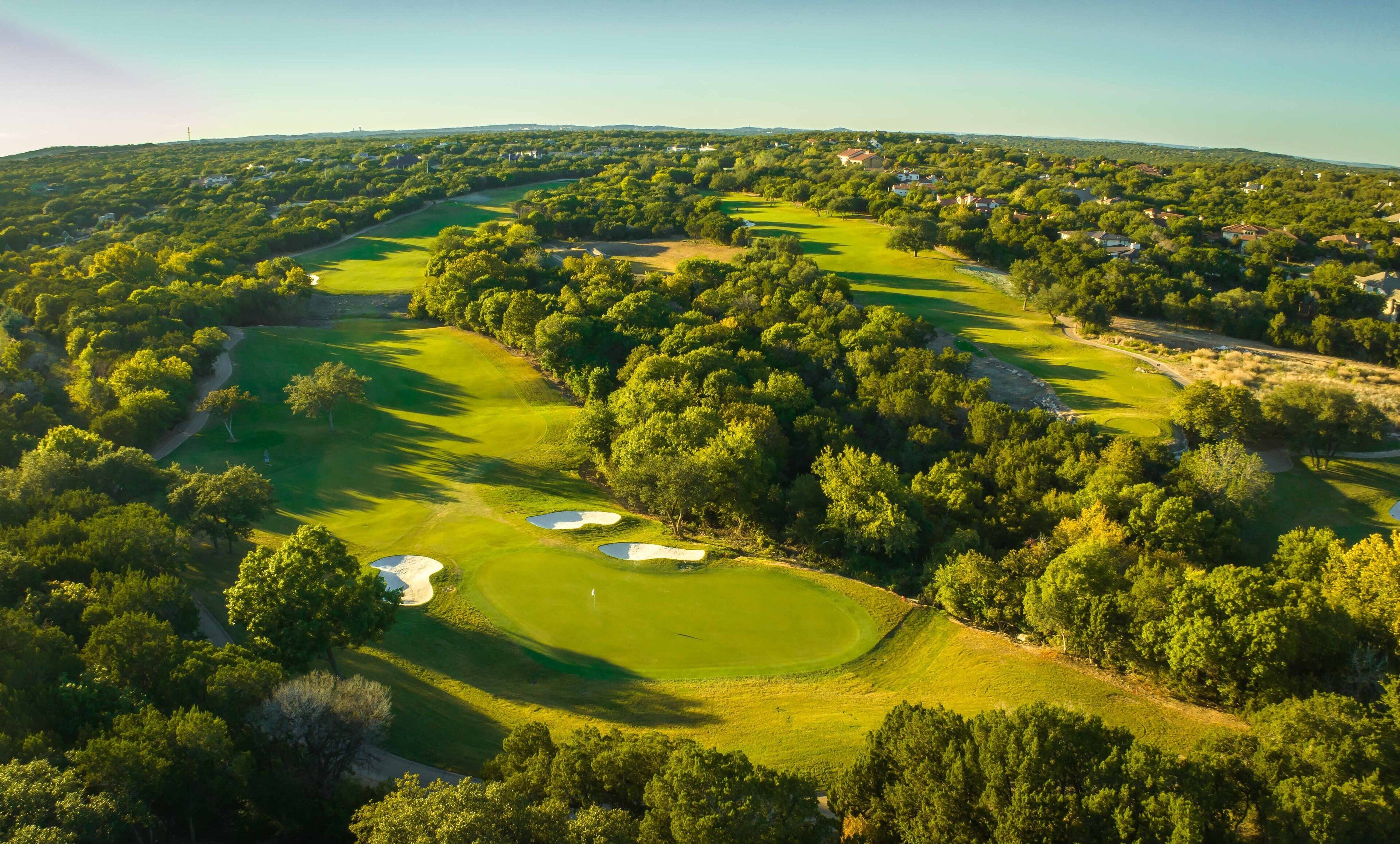 Vista aérea de un campo de golf con múltiples búnkeres y un césped bien cuidado.