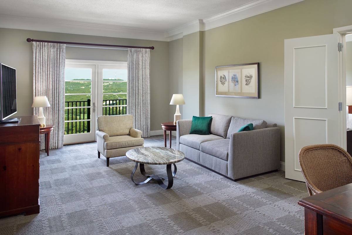 Ein Hotelzimmer mit Sofa, Sessel, kleinem runden Tisch und Fernseher.