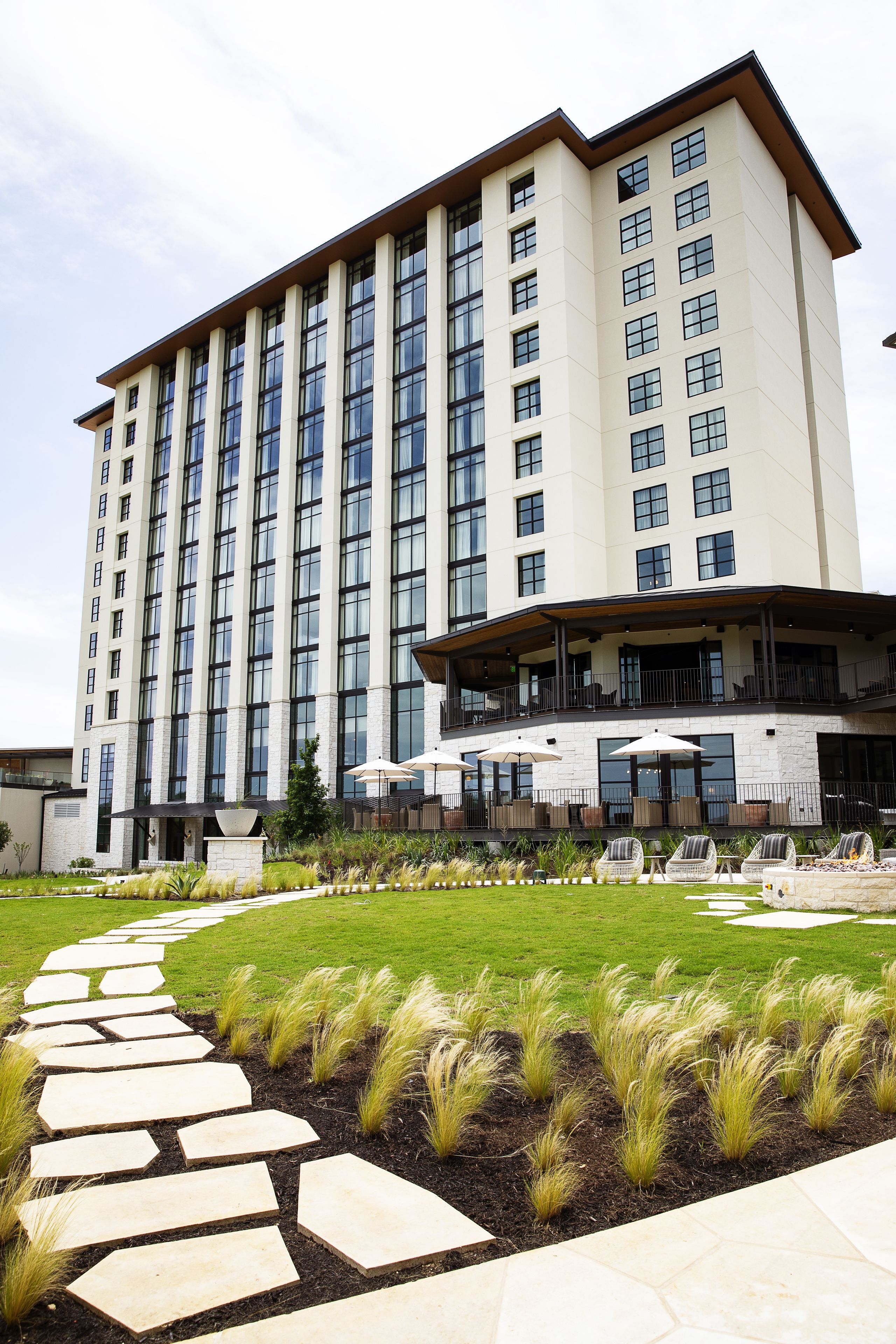 A modern hotel with a central courtyard, a covered outdoor seating area, and a well-maintained garden path.