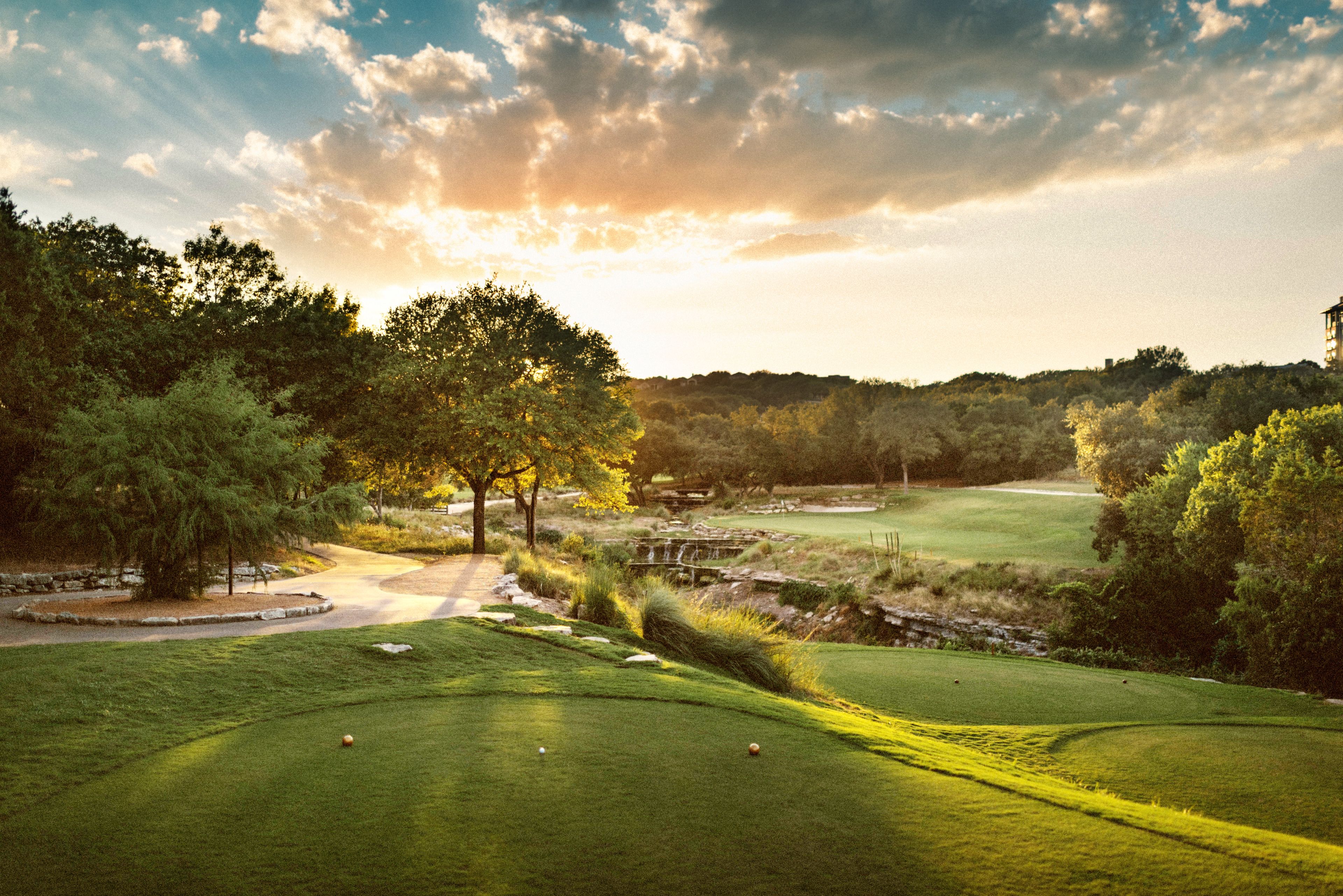 A golf course with a well-maintained green, a bridge, and trees in the background.