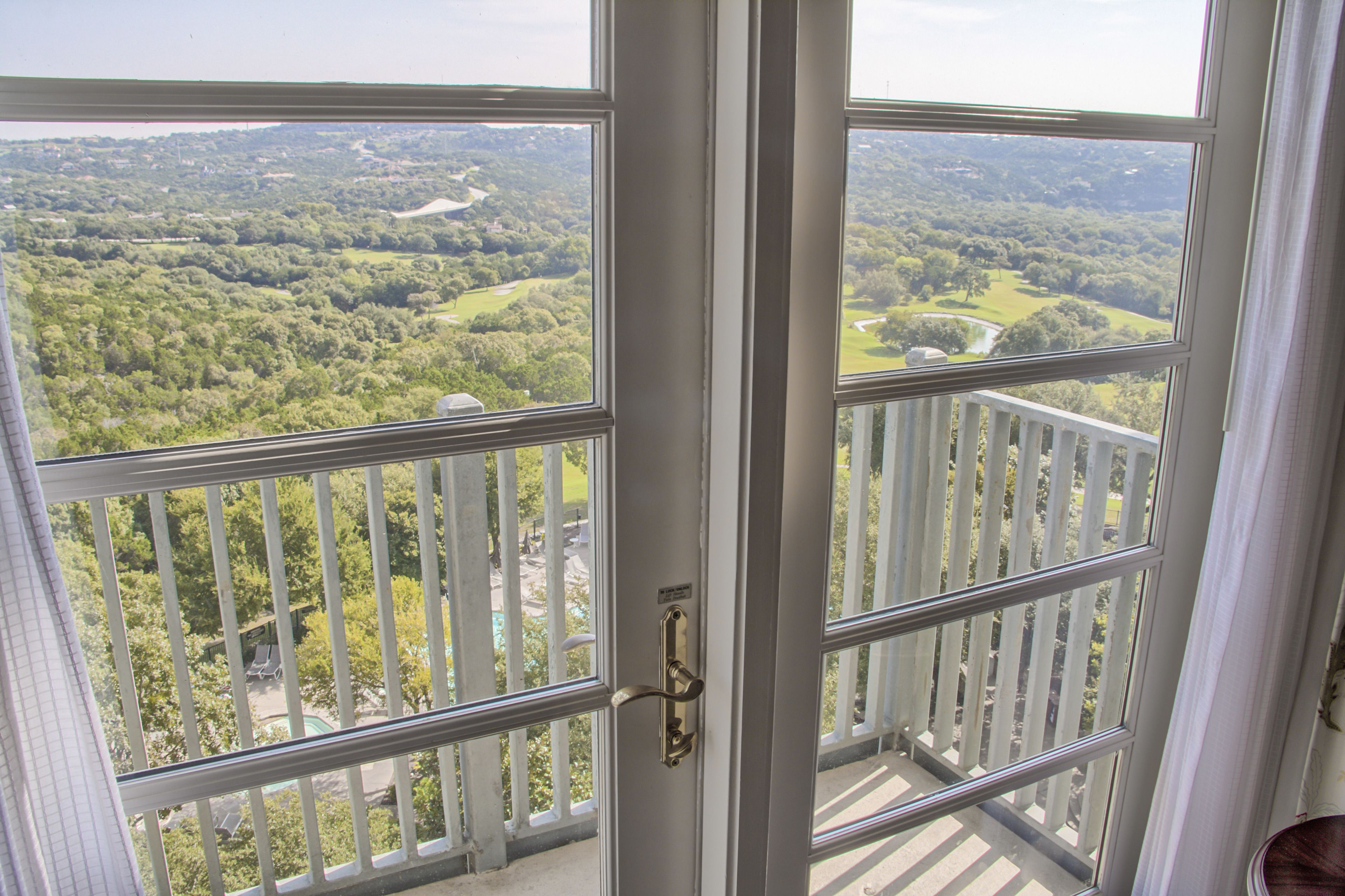 A balcony with a view of a green landscape and a body of water.