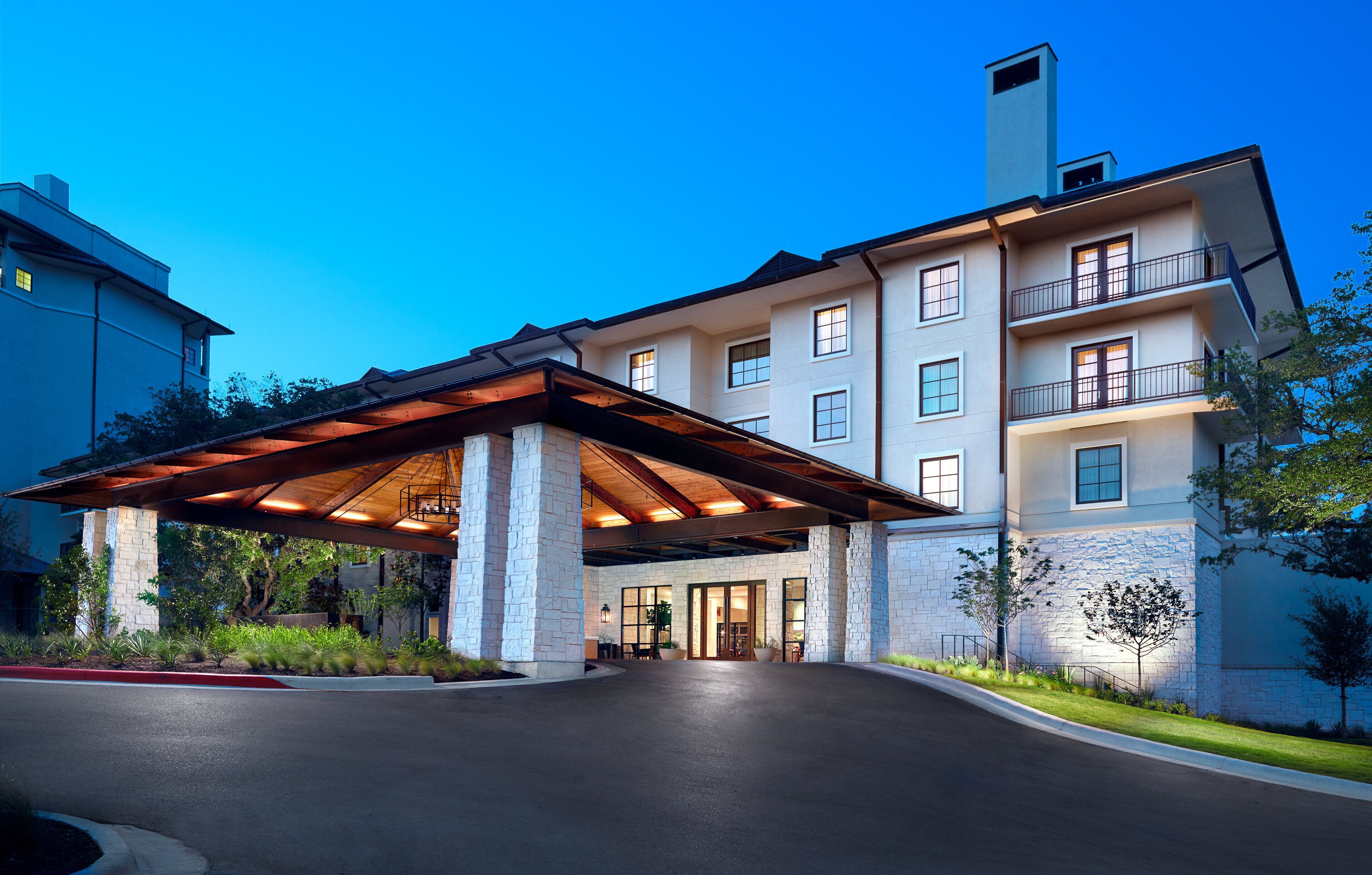 A multi-story hotel with a covered entrance, stone facade, and balconies.