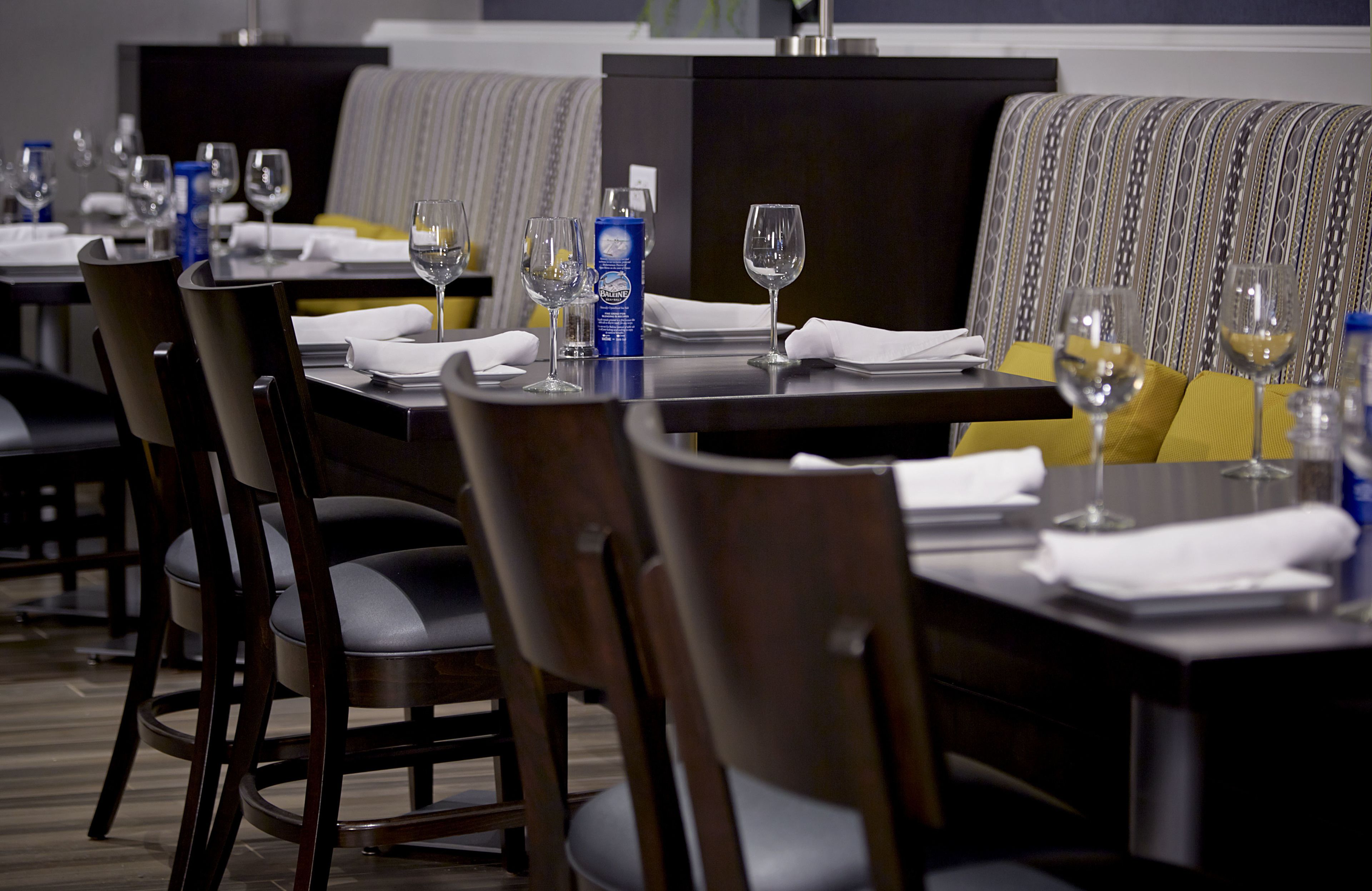 A restaurant setting with tables set for dining, including wine glasses and napkins.