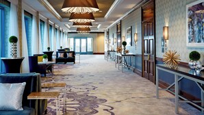 Un hall d’hôtel spacieux, doté d’un tapis à motifs, de meubles modernes et d’un grand lustre.