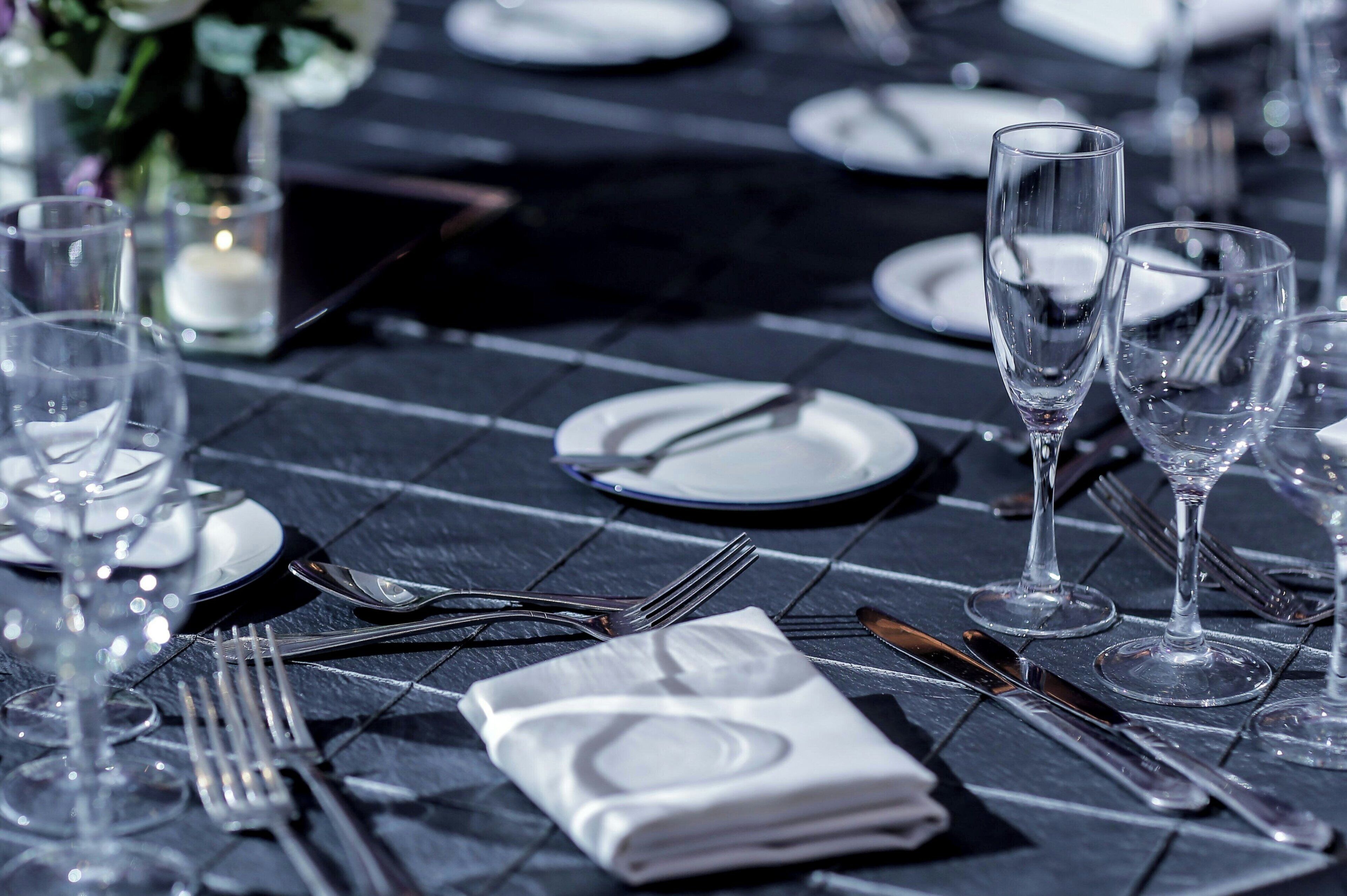 Mesa servida con platos, cubiertos y vasos, lo que sugiere una disposición para cenar formal.