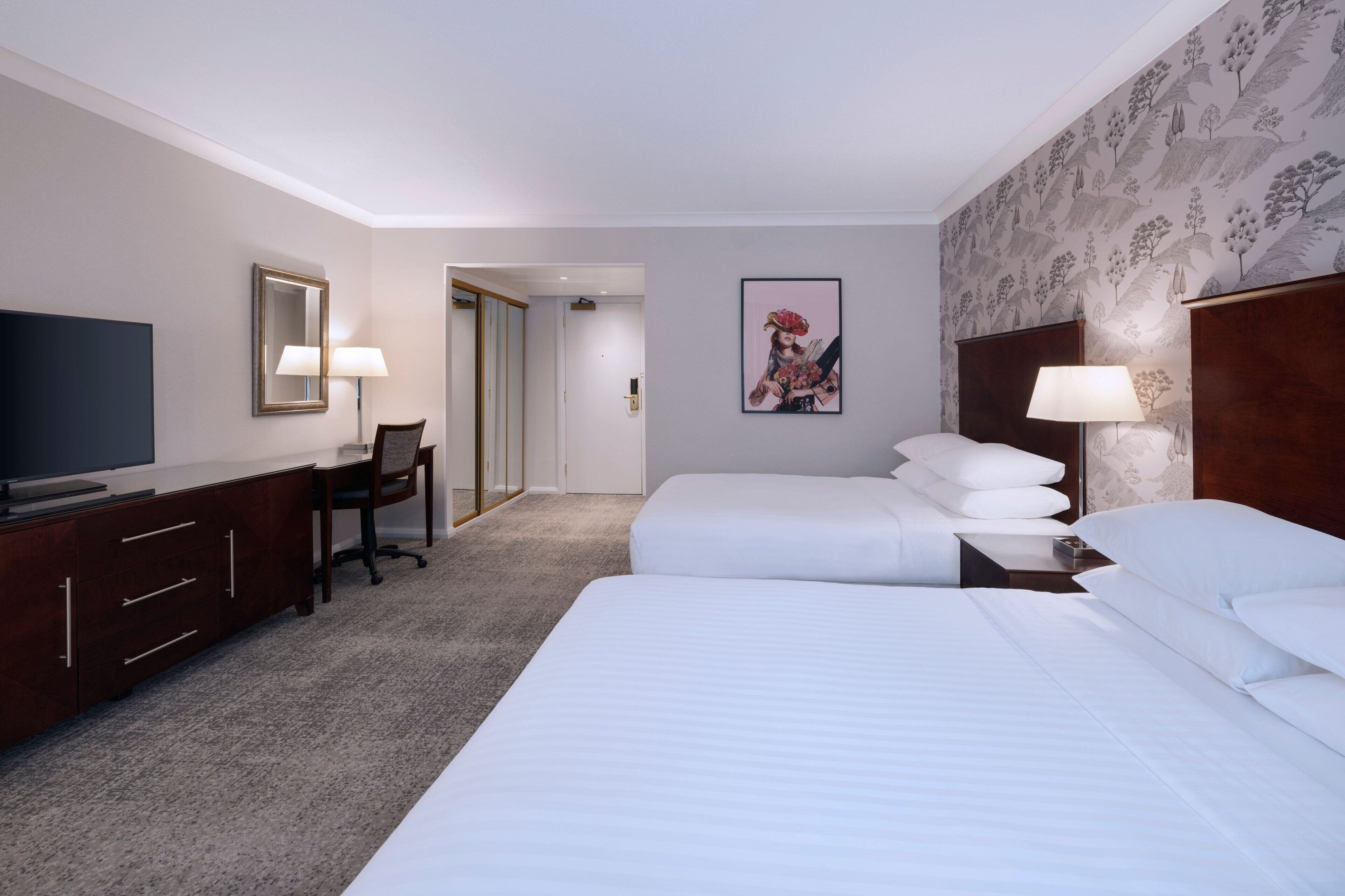 Habitación de hotel con una cama grande, un escritorio con silla, televisión y un cuadro en la pared.