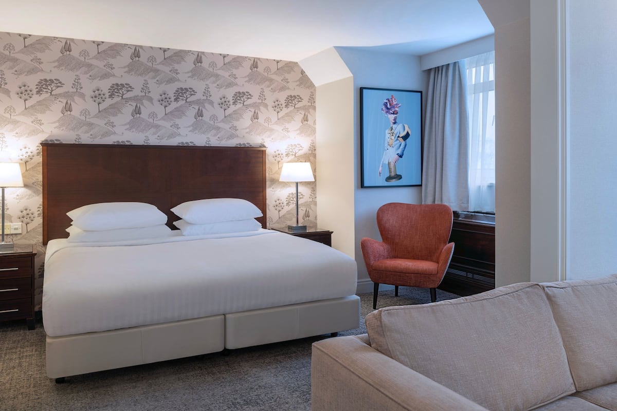 Une chambre d’hôtel avec un grand lit, une chaise, un bureau et un tableau au mur.