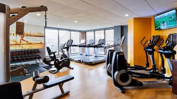 Une salle de sport équipée de tapis de course, de vélos elliptiques et de matériel de musculation.