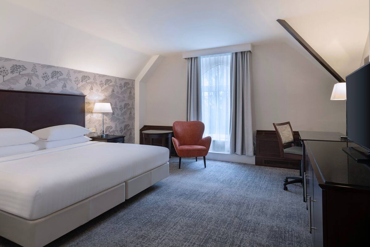 Une chambre d’hôtel avec un grand lit, un bureau, une chaise et un téléviseur.