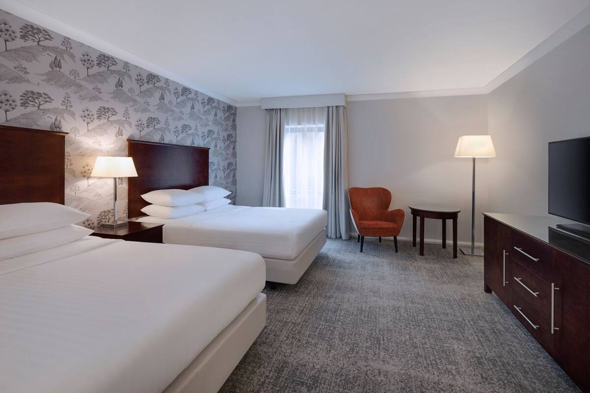 Une chambre d’hôtel avec deux lits, une télévision, un bureau et une chaise.