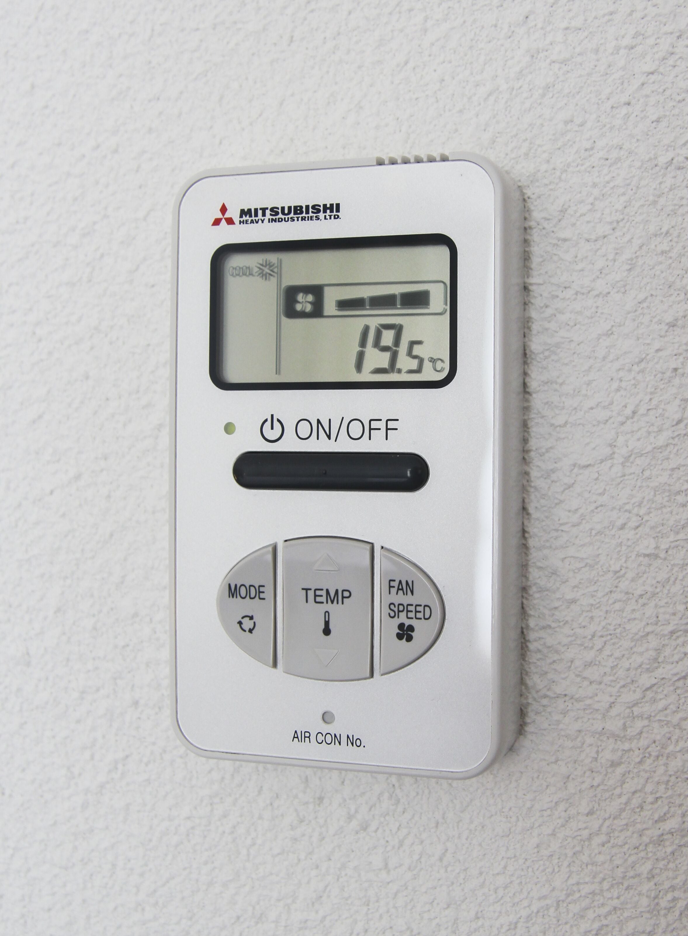 Een digitale thermostaat met Mitsubishi branding, waarop een temperatuur van 19,5°C wordt weergegeven, met knoppen voor AAN/UIT, MODUS, TEMPERATUUR, VENTILATORSNELHEID en AIRCO No.