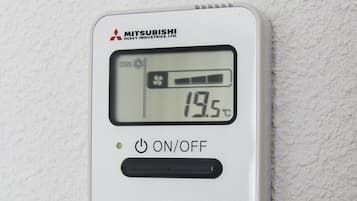 Een digitale thermostaat met Mitsubishi branding, waarop een temperatuur van 19,5°C wordt weergegeven, met knoppen voor AAN/UIT, MODUS, TEMPERATUUR, VENTILATORSNELHEID en AIRCO No.
