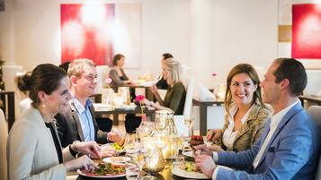 A group of people dining at a restaurant with a modern interior, featuring a table set with various dishes and drinks.