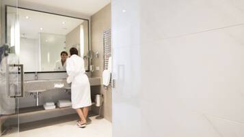 A modern bathroom with a glass shower enclosure, a large mirror, and a vanity with a sink and towel rack.