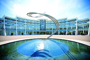 Un hotel moderno con piscina central y una llamativa escultura en espiral.